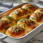 Freshly baked garlic butter bread rolls in white baking dish